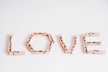 Wooden clothespins on a white background with the inscription the word love. View from above