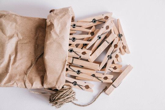 Wooden Clothespins In Paper Bag With Rope On White Background. View From Above. Place For Your Text