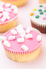 Colorful cupcakes on a pink background.