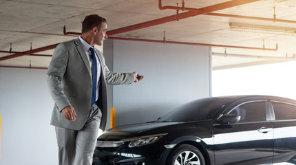 Opportunities. Businessman in grey suit parks his car at parking lot. Copy space on the right side