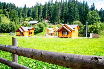New house construction on a green lawn between two finished wooden houses. Wooden house made of logs. Building a new house from scratch in the summer. sunny day
