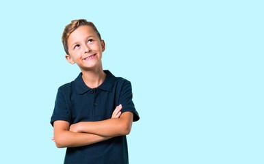 Little boy stand and looking up on blue background © luismolinero