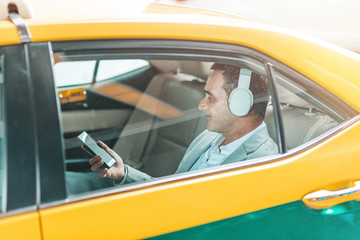 Be comfortable. Businessman with headphones rides in a taxi. © Adamov