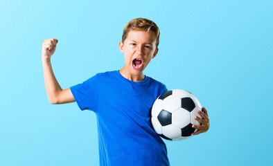 Lucky boy playing soccer on blue background