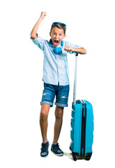 Full body of Kid with sunglasses and headphones traveling with his suitcase celebrating a victory on isolated white background