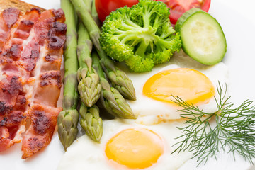 Fried eggs with bacon on the wooden table.