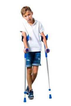 Little Kid With Crutches On Isolated White Background