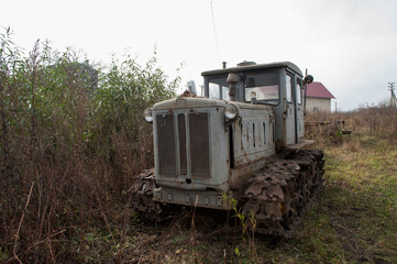 Fototapeta premium Vintage grey broken bulldozer. Abandoned old rusty crawler tractor near the field