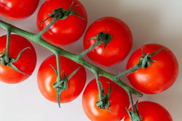 Fresh cherry tomatoes on twig on white background. Macro, flat lay. Horizontal