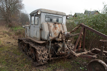 Vintage grey broken bulldozer. Abandoned old rusty crawler tractor near the field