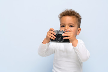 kid over isolated blue background holding a camera