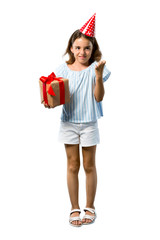 A full-length shot of a Little girl at a birthday party holding a gift annoyed angry in furious gesture on isolated white background