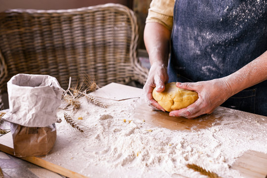 Female hands and dough. A woman is preparing a dough for home baking. Rustic style photo. Wooden table and flour. Free space for text.