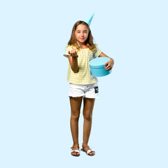 Obraz premium Full body of Little girl at a birthday party holding a gift presenting and inviting to come on blue background