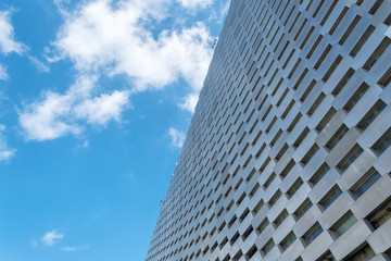 Fototapeta premium Facade of a modern metal building against a cloudy sky. Bottom view Architecture