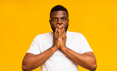 Shocked african guy shut his mouth in amazement