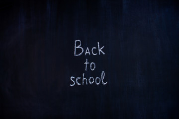 Obraz premium White chalk handwritten inscription of back to school in center of blackboard background. Preparing pupils children students for study at university, college, academy. Autumn mood concept.