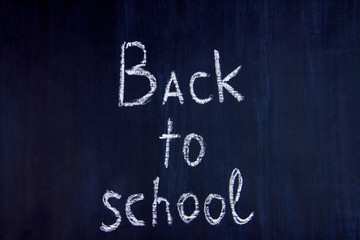 White chalk handwritten inscription of back to school in center of blackboard background. Preparing pupils children students for study at university, college, academy. Autumn mood concept.