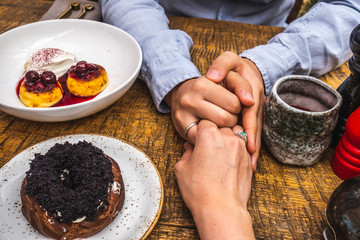 newlyweds hold hands close-up in a cafe