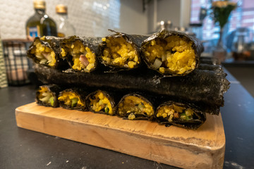 Homemade sushi rolls on cutting board on kitchen