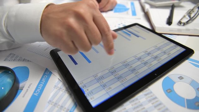 Businessman working and calculating, reads and writes reports. Using tablet pc. Office employee, table closeup. Business financial accounting concept.