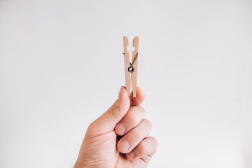 Male hand holding wooden clothespin on white background