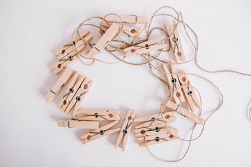 Wooden clothespins with rope on white background. View from above. Place for your text