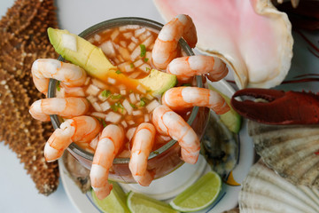 Fresh shrimp cocktail with onion, cilantro, avocado and lemon in tomato sauce.