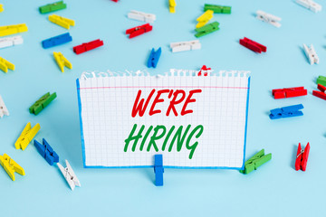 Text sign showing We Re Hiring. Business photo showcasing process of reviewing applications and finding candidates Colored clothespin papers empty reminder blue floor background office pin