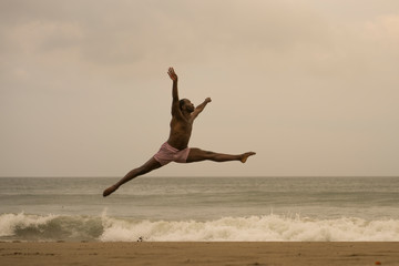 Obraz premium dramatic contemporary dance choreographer doing ballet beach workout . young attractive and athletic afro black American man dancing on sunrise jumping