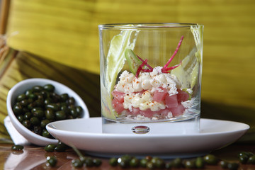 Cocktail of tuna, avocado, capers and chili accompanied by a glass of white wine.