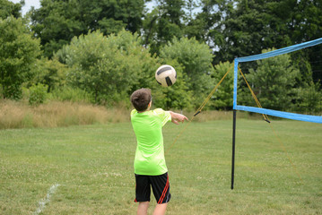 Boy setting ball on outdoors grass doubles game