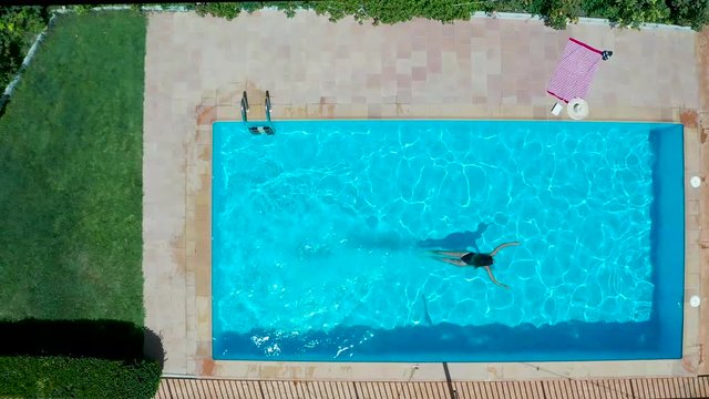 Nadadora profesional nadando en una piscina privada, vista cenital desde dron