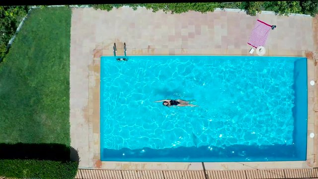 Nadadora profesional nadando en una piscina privada, vista cenital desde dron