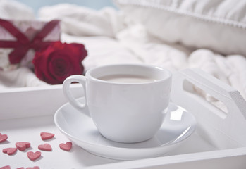 Close up of cup of tea with red rose on the white tray