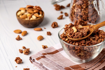 Obraz na płótnie Canvas Granola crispy muesli with natural honey, chocolate and nuts in a glass bowl against a white background, healthy food, horizontal orientation