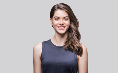 Obraz premium Beautiful young woman portrait. Smiling girl looking to camera. Isolated on gray background