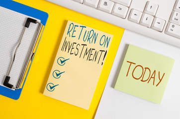 Writing note showing Return On Investment. Business concept for perforanalysisce measure used evaluate efficiency of investment Paper with copy space and keyboard above orange background table