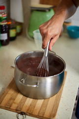 Preparing homemade chocolate pudding, closeup on hands