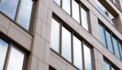 Modern architecture pattern in apartment building. bright sky and clouds reflecting on the windows of the building. modular build pattern.