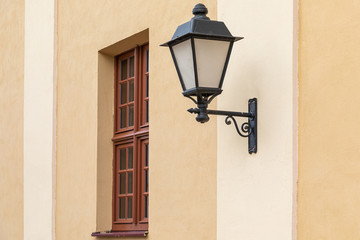 Fototapeta na wymiar Black wrought streetlamp on light wall