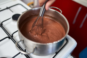 Preparing homemade chocolate pudding, closeup on hands
