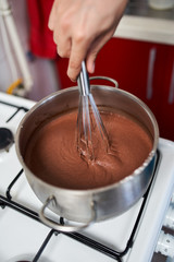 Fototapeta premium Preparing homemade chocolate pudding, closeup on hands