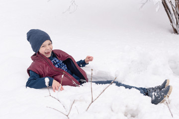 Fototapeta na wymiar school boy having fun in winter in the snow after school
