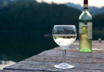 relaxing with a glass  german white wine with blurred bottle in backgroundon lake at evening