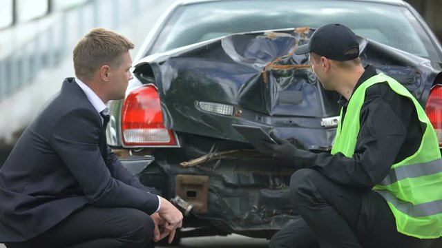 Insurance company worker counting compensation after car crash on tablet PC