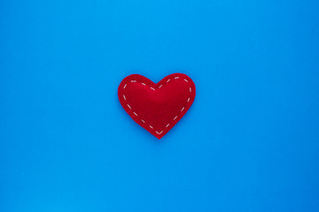 Red heart fabric with white threads on a blue background Love, romance concept. Felt bright hearts with embroidered lines.