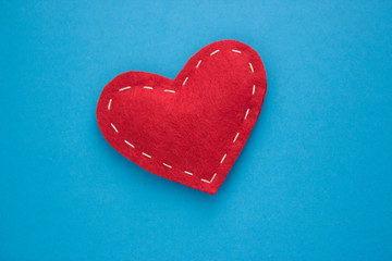 Red heart fabric with white threads on a blue background Love, romance concept. Felt bright hearts...