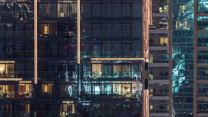 Lights in windows of modern multiple story building in urban setting at night timelapse