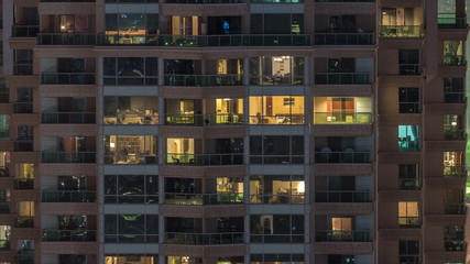 Fototapeta na wymiar Lights in windows of modern multiple story building in urban setting at night timelapse